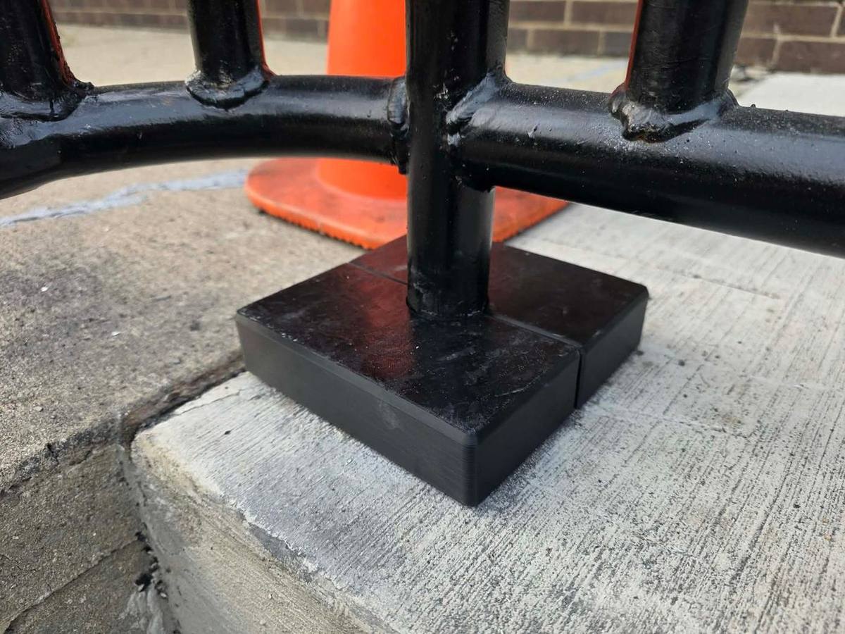 Welded and painted handrail base plate anchored to a concrete step