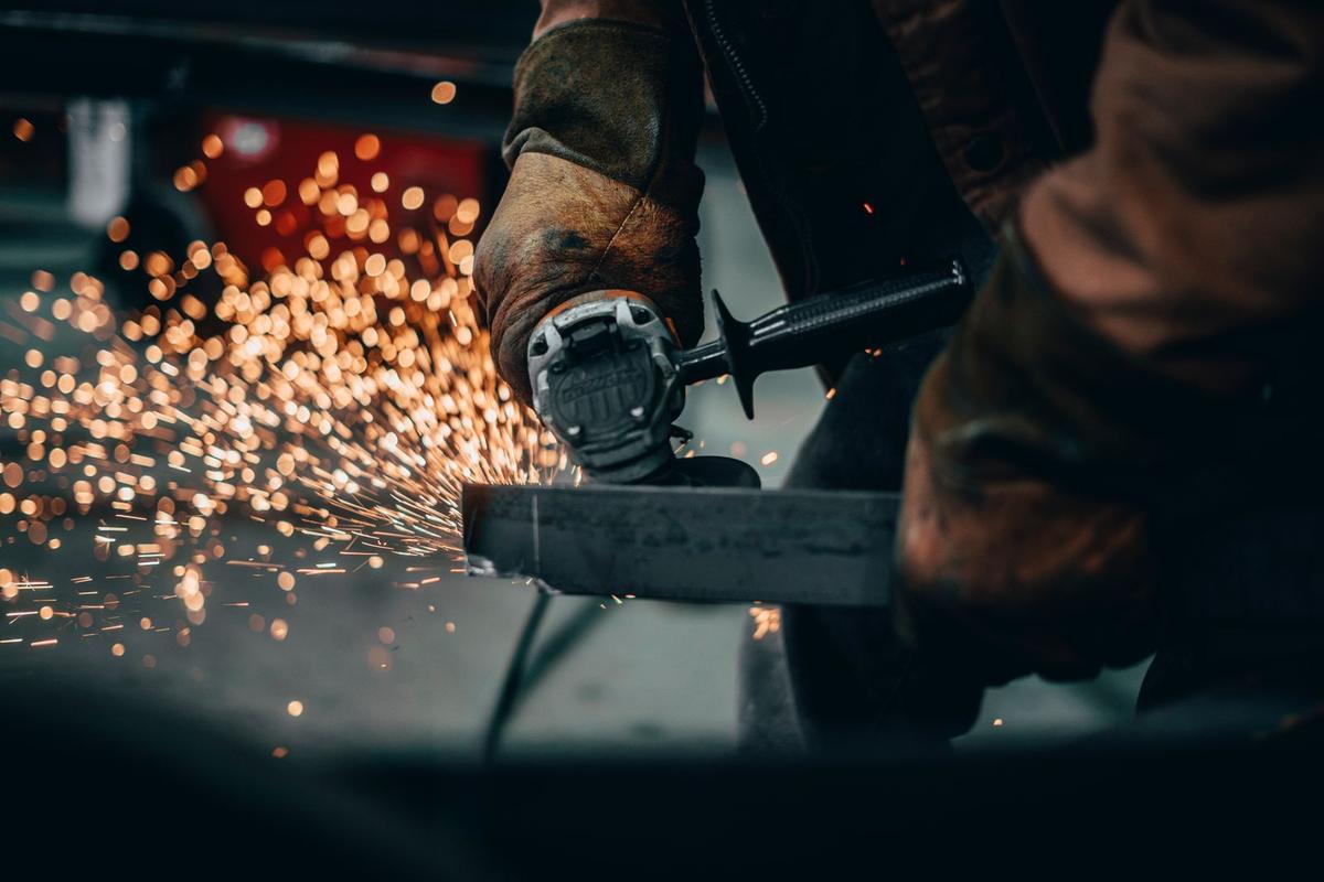 Angle grinder throwing sparks while dressing a steel section