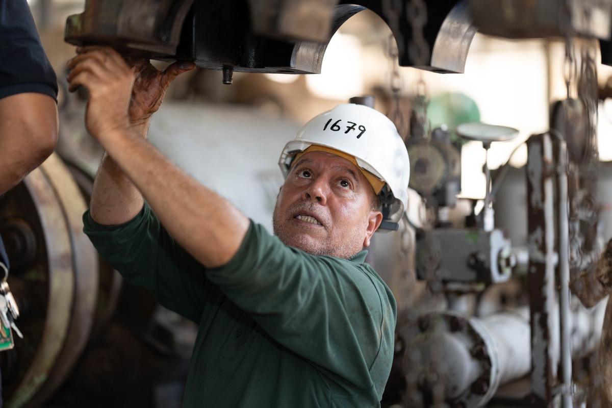Maintenance technician in a hard hat working on overhead plant equipment