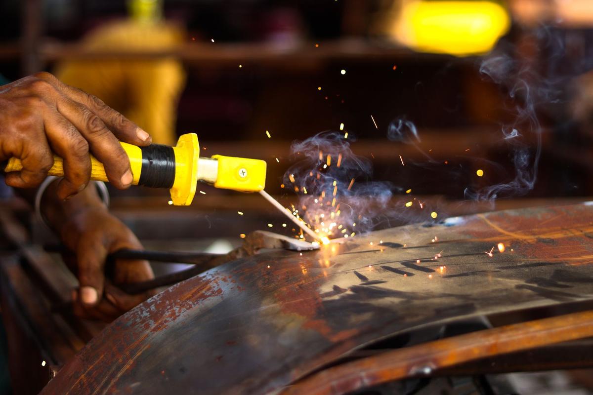 Welder running a torch along a curved steel pipe with sparks flying